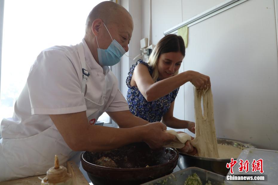 ロシア人留學生?KarpovichPolinaさんに生地作りを教える渠口周家肉餅の伝承人?周振祥さん（9月15日撮影?陳宏儒）。